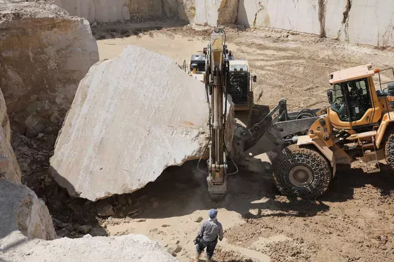 Excavator moving a marble block at the quarry